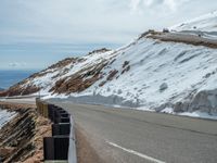 an empty road and a hill overlook the view of mountains and clouds and blue sky