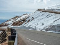 an empty road and a hill overlook the view of mountains and clouds and blue sky