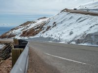 an empty road and a hill overlook the view of mountains and clouds and blue sky