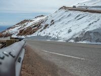 an empty road and a hill overlook the view of mountains and clouds and blue sky