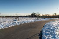 the long road runs along both sides of the snow covered field with no people on it