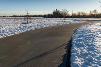 the long road runs along both sides of the snow covered field with no people on it