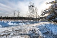 a snow covered road with a stop sign in front of it in front of a tree