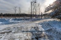 a snow covered road with a stop sign in front of it in front of a tree