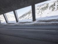a car is driving through the snow covered roadway near a bridge on a mountain side