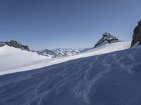 a large snow covered ski slope with some mountains in the background and one snow boarder is in mid - air