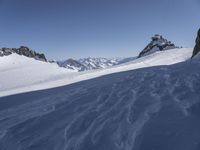 a large snow covered ski slope with some mountains in the background and one snow boarder is in mid - air