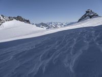 a large snow covered ski slope with some mountains in the background and one snow boarder is in mid - air