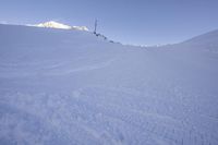 a person riding skis on top of a snow covered slope in the mountains behind him