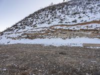 a bench in the middle of the snow covered slope near a mountain top, covered in ice