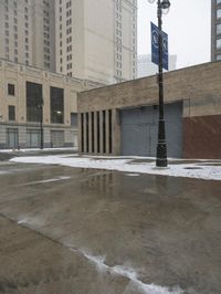 a street pole sitting on top of snow covered ground near tall buildings in the city