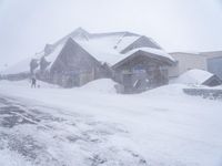 a snow covered street with houses on the side and snow in front of them,