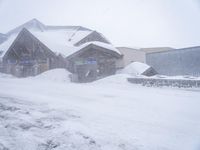 a snow covered street with houses on the side and snow in front of them,