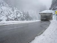 a snow covered street with traffic on it and a tunnel over the road below that