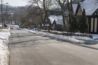 the snow - covered streets of a town are empty, with many buildings and trees in the foreground