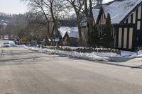 the snow - covered streets of a town are empty, with many buildings and trees in the foreground