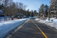 a snow covered road with no traffic on it with trees and cars in the background