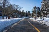 a snow covered road with no traffic on it with trees and cars in the background