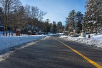 a snow covered road with no traffic on it with trees and cars in the background