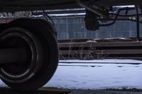 train wheels on the side of a railroad platform in winter time, with snow and weeds