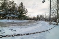 a long chain next to a street light in the snow - covered road area at a park