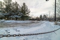 a long chain next to a street light in the snow - covered road area at a park