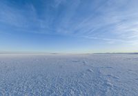 a snow field covered in snow under a blue sky with clouds above it and the snow in the background