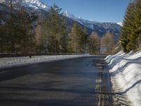 a snow filled road on a clear sunny day with snow all around the roadway and trees in the middle