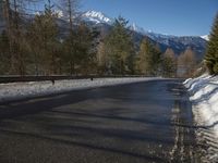 a snow filled road on a clear sunny day with snow all around the roadway and trees in the middle