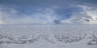 a landscape of snow, clouds, and a large cloud in the sky on a very cloudy day