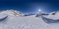 the view of a small snow park from below of a mountain range with lots of snow