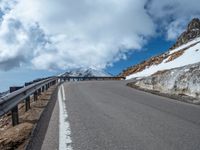 a snow covered road is near a very steep cliff on a clear day the wall is filled with snow and snow