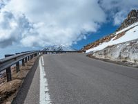 a snow covered road is near a very steep cliff on a clear day the wall is filled with snow and snow