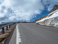 a snow covered road is near a very steep cliff on a clear day the wall is filled with snow and snow