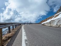 a snow covered road is near a very steep cliff on a clear day the wall is filled with snow and snow