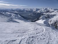 snow skiers going down a snowy mountain with mountains behind them, with a yellow sign above them