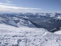 snow skiers going down a snowy mountain with mountains behind them, with a yellow sign above them