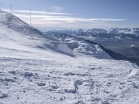 snow skiers going down a snowy mountain with mountains behind them, with a yellow sign above them