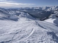 snow skiers going down a snowy mountain with mountains behind them, with a yellow sign above them