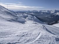 snow skiers going down a snowy mountain with mountains behind them, with a yellow sign above them