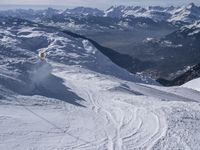 snow skiers going down a snowy mountain with mountains behind them, with a yellow sign above them