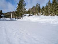 a man that is skiing on a snow trail in the snow - covered ground near the cabin