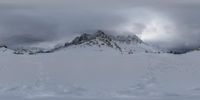 a lone snowboarder in the middle of a mountain scene with cloudy clouds and a lone peak