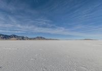 a snowboarder stands in the middle of an icy field, in a mountainous area