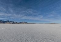 a snowboarder stands in the middle of an icy field, in a mountainous area