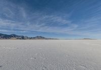 a snowboarder stands in the middle of an icy field, in a mountainous area