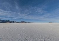 a snowboarder stands in the middle of an icy field, in a mountainous area