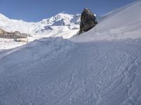 people on snowboards going down a snowy hill next to the ski resort at the base of a mountain