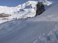 people on snowboards going down a snowy hill next to the ski resort at the base of a mountain