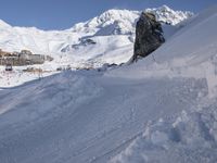 people on snowboards going down a snowy hill next to the ski resort at the base of a mountain